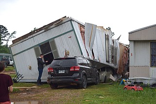 A damaged mobile home upended by Wednesday's tornado rests on a vehicle in a trailer park off Thunder Road. (The Sentinel-Record/Donald Cross)